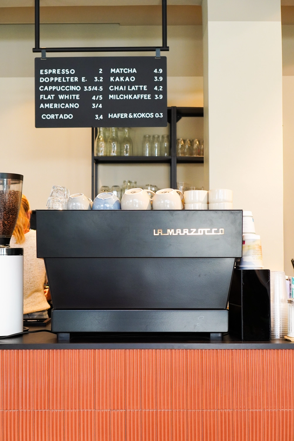 NOA - Café Brunch Konzept - Tassen auf der Kaffeemaschine und hängendes Menüschild